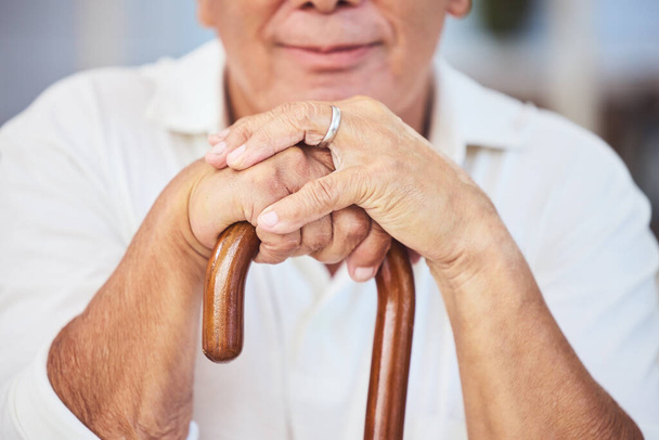 Old man hands, walking stick and disability from osteoporosis, arthritis and aging. Closeup of lonely, retirement and disabled senior widower with dementia, pain and wooden cane for support. - Фото, изображение