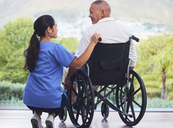 Здравоохранение, инвалидность и мужчина в инвалидной коляске с медсестрой на пенсии или дома престарелых патио. Старший по возрасту, счастливый дедушка-инвалид и женщина-сиделка с улыбкой наслаждаясь видом в больнице или клинике. - Фото, изображение