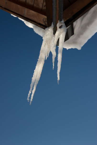 Kylmä jääpuikko puukatolla lunta ja sininen taivas talvella
 - Valokuva, kuva