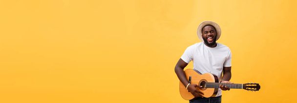 Bonito guitarrista afro-americano estilo retro tocando guitarra acústica isolada em fundo amarelo
 - Foto, Imagem