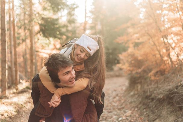 Young romantic couple in the woods. Piggyback riding. Happy together - Фото, изображение