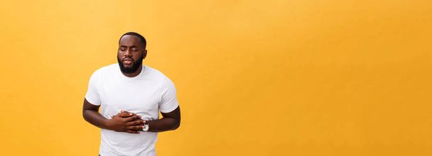 Afro-amerikai fiatalember visel fehér póló, kezével a gyomor, mert hányinger, fájdalmas betegség, rossz közérzet. Ache koncepció. - Fotó, kép