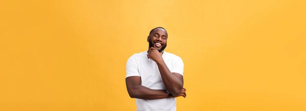 Porträt eines modernen jungen schwarzen Mannes, der mit verschränkten Armen auf gelbem Hintergrund lächelt. - Foto, Bild