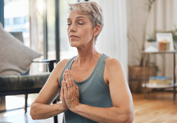 Senior woman, yoga and meditation at home for exercise, wellness and health during zen practice for peace, balance and mindfulness. Fitness, retirement and fit old lady in prayer position to meditate. - Фото, зображення