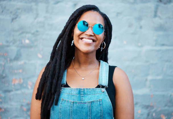 Portrait of black woman with sunglasses in the city and a smile on her face. Young fashion model, summer and happy girl with glasses, trendy accessories and street clothes smiling in an urban town. - Фото, изображение