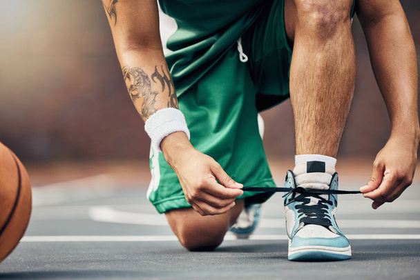 Basketball player shoes on court, start game and hands tie sneakers shoelaces with ball. Sports man prepare for competition, player training in summer and strong athlete kneeling ready for workout. - Photo, image