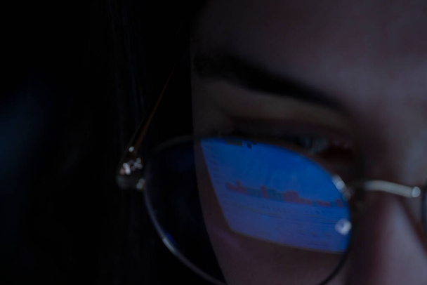 joven, mirando el mercado de valores por la noche, el mismo mercado se ve en el reflejo de sus gafas, México América Latina - Foto, Imagen
