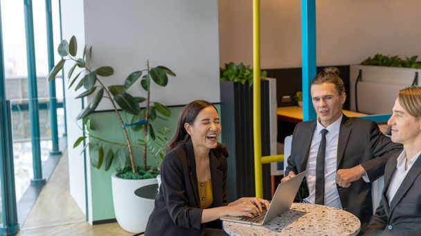 Grupa menedżerów z różnych kultur korzysta z laptopa, aby przygotować nowy projekt dla klienta w zielonym biurze. mężczyzna i kobieta współpracownicy pracują razem na zielony taras przestrzeń - Zdjęcie, obraz