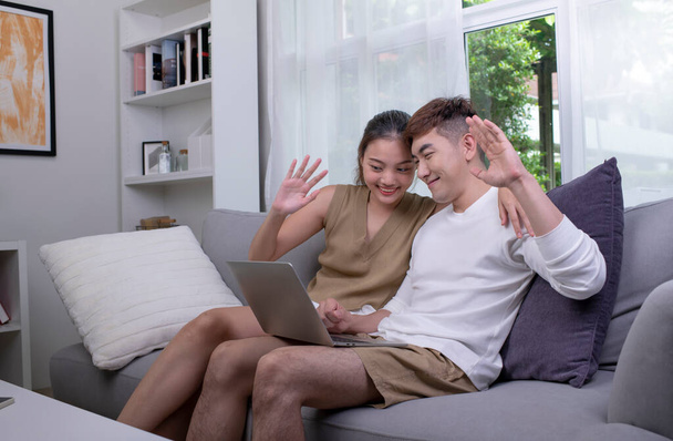 Aziatisch paar met behulp van laptop om verbinding te maken met familie voor videogesprek. Man en vrouw met laptop in de woonkamer thuis. - Foto, afbeelding
