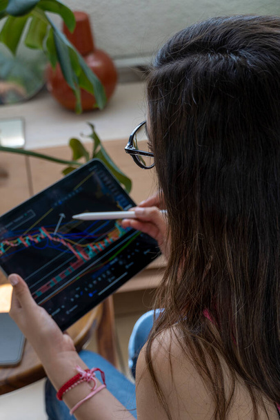 Молодая женщина работает в современном офисе. Технический график цен и индикатор, красный и зеленый свечи график и биржевой торговли компьютерного экрана. Двойное воздействие. Трейдер анализирует данные - Фото, изображение