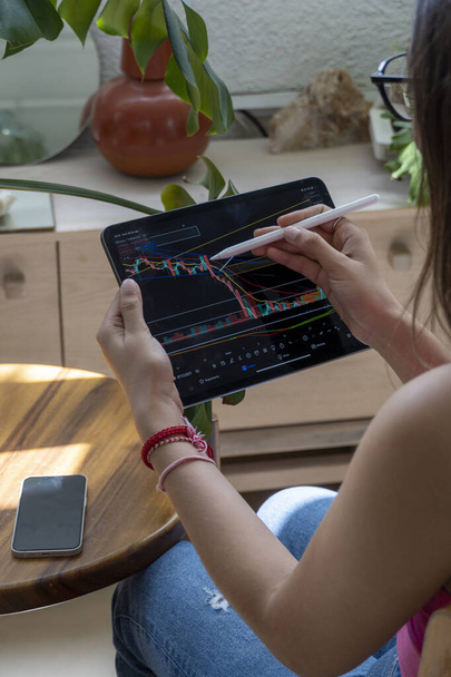 giovane donna, guardando il mercato azionario sul suo tablet, mentre attingendo al grafico le sue proiezioni di borsa e il movimento degli asset, messico latino americano - Foto, immagini