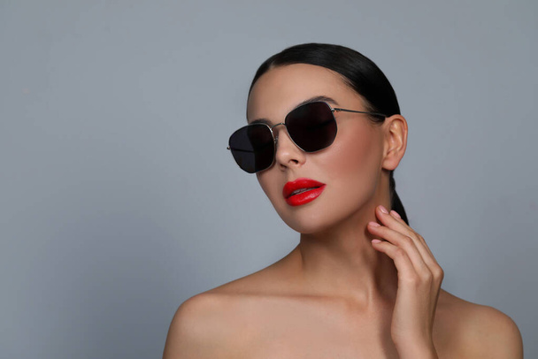 Attractive woman in fashionable sunglasses against grey background. Space for text - 写真・画像
