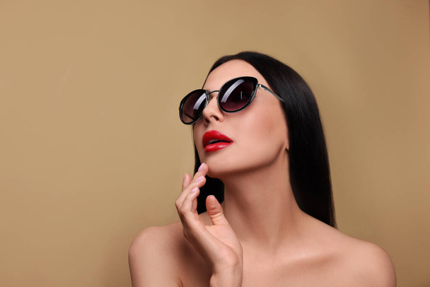 Attractive woman in fashionable sunglasses against beige background. Space for text - Φωτογραφία, εικόνα