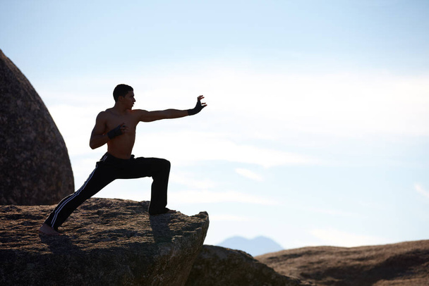 Plně soustředěný na horu. Samec kickboxer trénující na okraji útesu na hoře - Fotografie, Obrázek