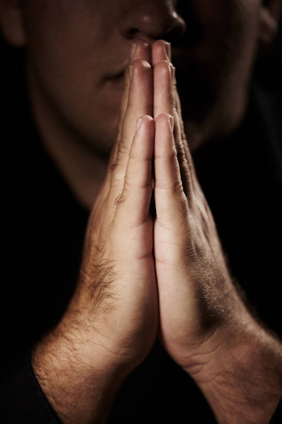 Seeking guidance from above. Hands placed together in prayer in front of a blurred face - 写真・画像