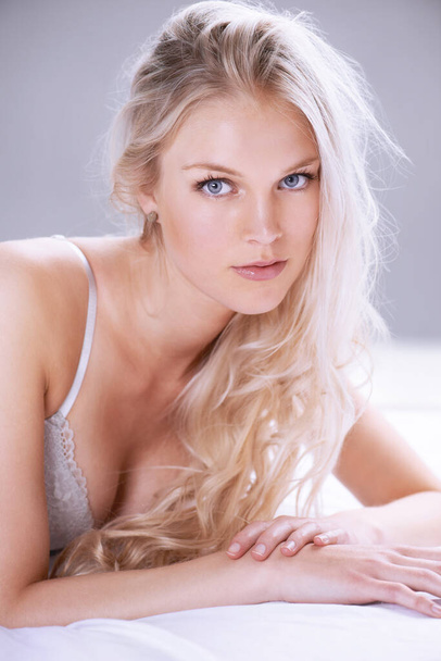 Zacht en zoet. close-up portret van een mooie jonge blonde vrouw liggend op een bed in lingerie - Foto, afbeelding