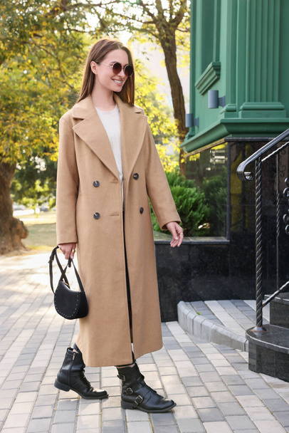 Fashionable young woman with stylish bag on city street - Photo, Image