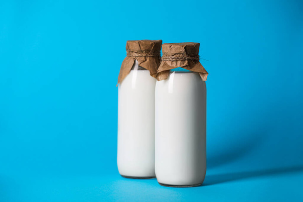 Tasty fresh milk in bottles on light blue background - Фото, изображение
