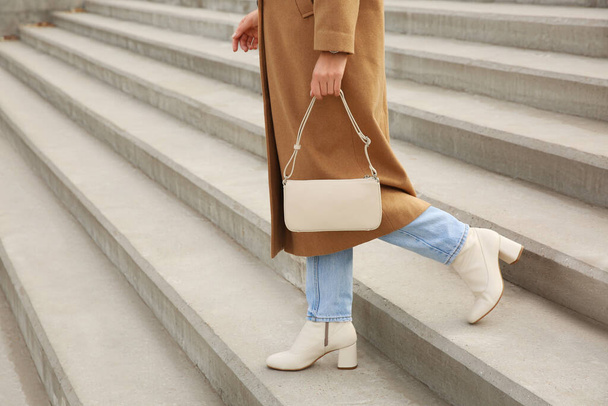 Stylish woman with trendy beige bag on stairs outdoors, closeup - Zdjęcie, obraz