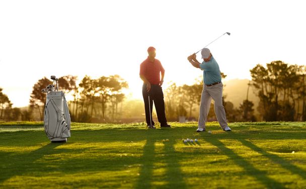 Mostrándole cómo se hace. Dos golfistas masculinos jugando una ronda de golf - Foto, imagen