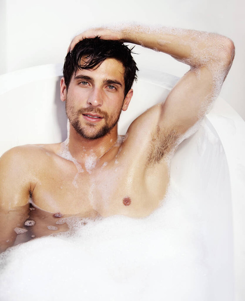 Seifig und sehr sexy. Porträt eines sexy Mannes, der sich in einer Badewanne voller Schaumbad entspannt - Foto, Bild