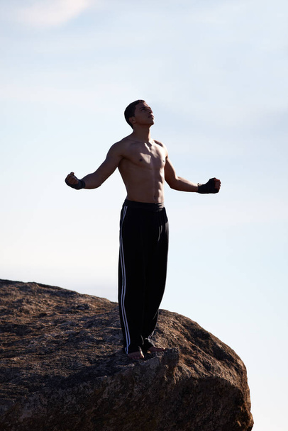 Je vrij voelen in de bergen. Een mannelijke kickboxer die naar de hemel kijkt terwijl hij op een bergrichel staat - Foto, afbeelding