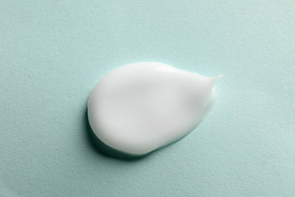 Sample of face cream on light blue background, top view - Foto, Bild