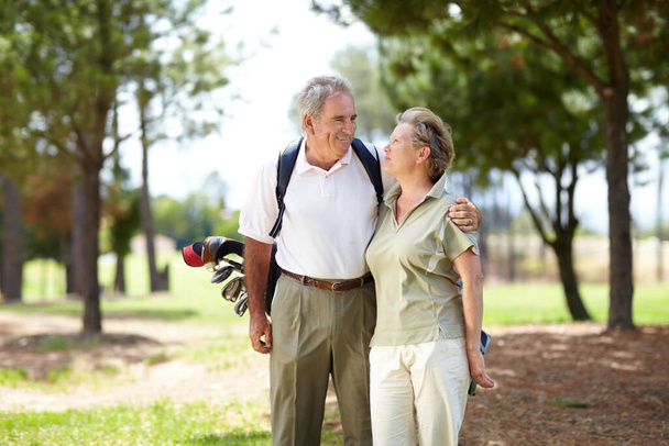 Time spent together playing our favourite game. A happily married senior couple standing together and smiling during a game of golf - Foto, Imagen
