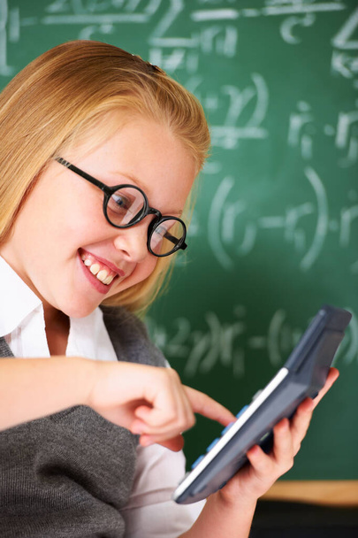 Calculators make maths fun. A cute blonde girl using a calculator in maths class - Photo, image