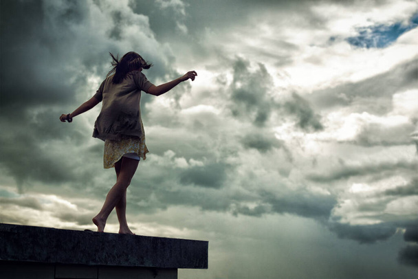 端を歩く。腕を伸ばして屋上を歩く若い女性 - 写真・画像