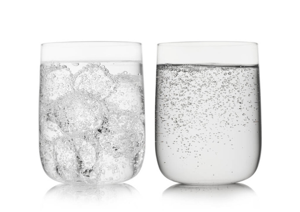 Sparkling natural mineral water with ice cubes in large glasses on white background. - 写真・画像