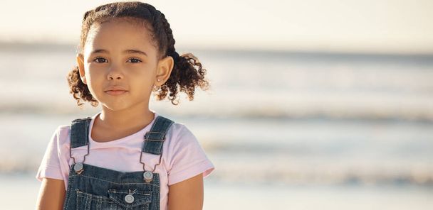 Portrait of girl child on holiday, at beach and standing in the sun by the ocean. Kid on summer holiday, travel to the coast in the sunshine and sand. Toddler by sea, childhood memory and on vacation. - Fotoğraf, Görsel
