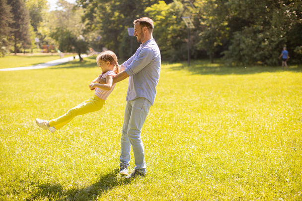公園で草の上で遊んでいるかわいい娘のお父さん - 写真・画像