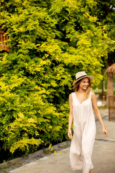 Pretty young woman with hat walking in the resort garden - 写真・画像