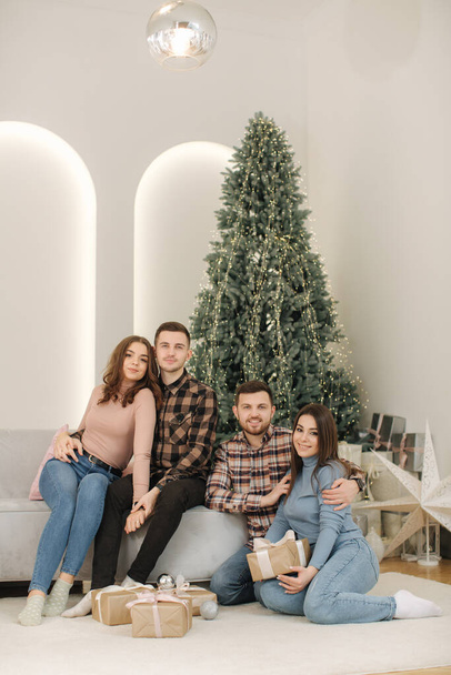 新年の写真撮影で妻と2人の弟。モミの木の前に美しい女性と男。クリスマス気分. - 写真・画像