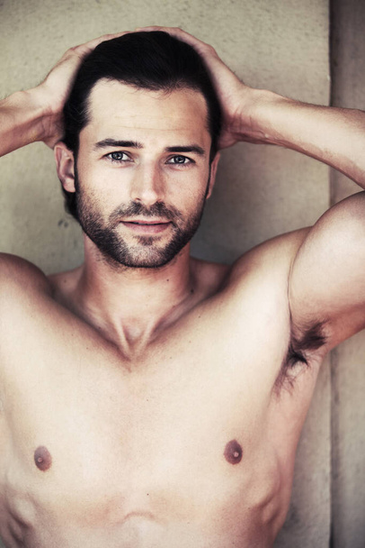 Rugged charm and masculinity. Handsome shirtless man pulling his hair back while looking at the camera - Photo, Image