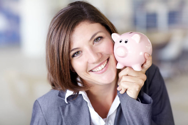 Make sure to save. Portrait of an attractive businesswoman holding a piggybank - Foto, Bild