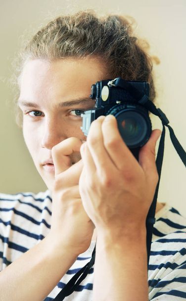 Au point. Portrait d'un jeune homme aux cheveux bouclés tenant une caméra sur son visage - Photo, image