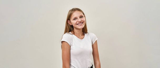 Partial of smiling caucasian teenage girl with braces looking at camera. Beautiful female child of zoomer generation. Concept of modern youngster lifestyle. White background. Studio shoot. Copy space - Valokuva, kuva