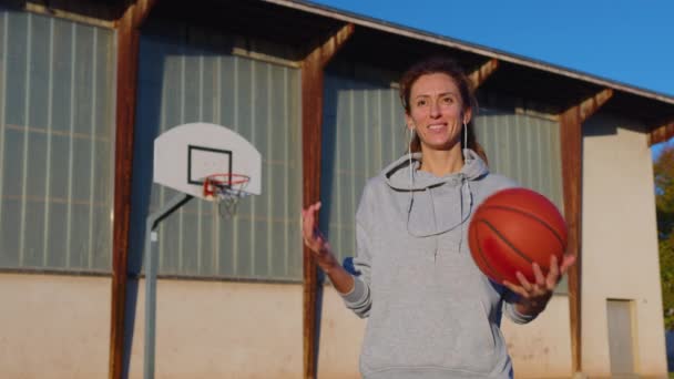 Porträt eines Mädchens mit einem Basketball auf einem Sport-Basketballfeld bei Sonnenuntergang. Hochwertiges 4k Filmmaterial - Filmmaterial, Video