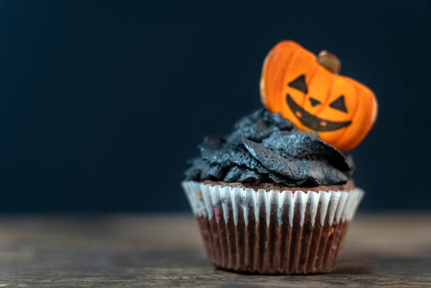 Leckere Halloween-Party schwarzer Cupcake mit Lebkuchen auf schwarzem Hintergrund. Kopierraum - Foto, Bild