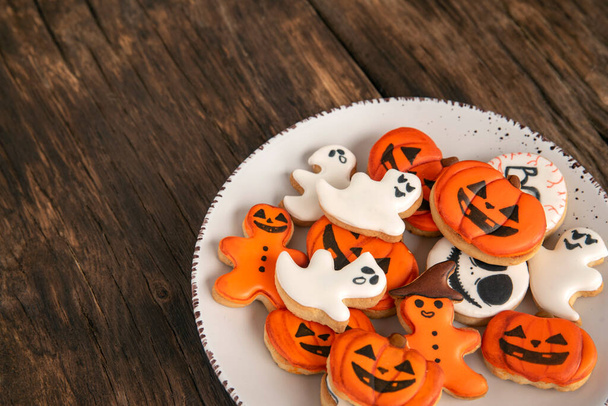 Πορτοκαλί Halloween μπισκότα σε σχήμα κολοκύθας φαντάσματα σε μεγάλο πιάτο σε ένα ξύλινο τραπέζι. Θέση για κείμενο. Άνω όψη. - Φωτογραφία, εικόνα