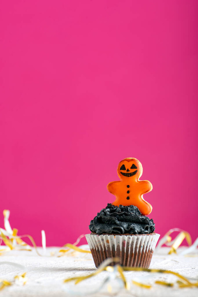 ハロウィンジンジャーブレッドクッキーカップケーキ.ピンクの背景にハロウィンパーティーの装飾が施された自家製マフィン. - 写真・画像