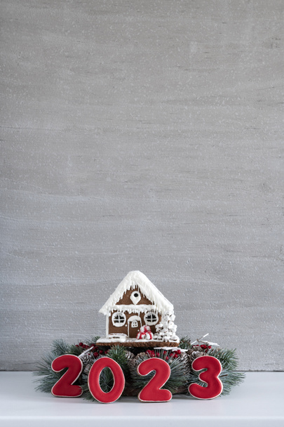 ジンジャーブレッドハウスと碑文2023 。メリークリスマス背景、コピースペース。背景に薄灰色の壁. - 写真・画像