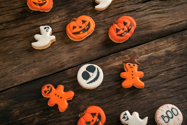 Хэллоуин имбирное печенье в виде тыквы и призраков на деревянном столе. Улыбающееся печенье. Вид сверху - Фото, изображение