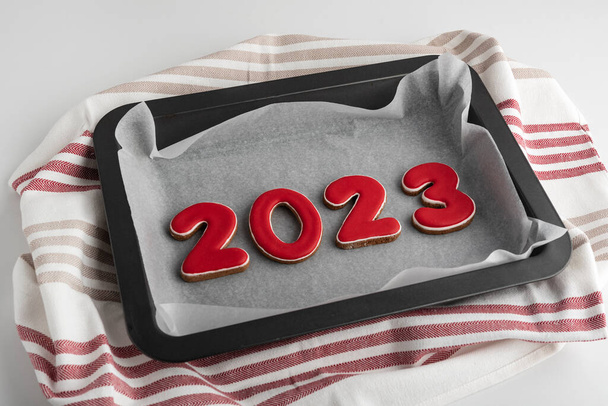 Bir çift kırmızı numara 2023, fırın tepsisinde zencefilli kurabiye. Geleneksel Noel kurabiyesi. - Fotoğraf, Görsel
