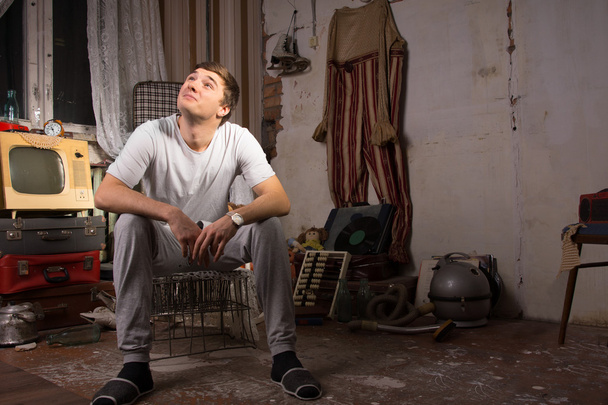 Sitting Young Man at Junked Room Looking Up - 写真・画像