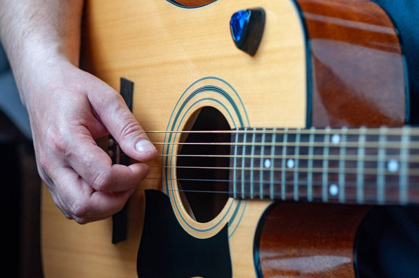 The musician plays the acoustic guitar. Musician's hand close-up. - Foto, afbeelding