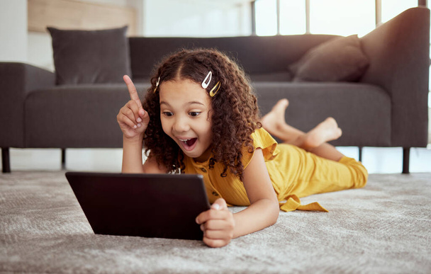 Pensamiento creativo, aprendizaje de la tableta y video de educación de la muchacha en Internet, idea de planificación con la tecnología y entusiasmado con la aplicación web en el piso de la sala de estar. Niño con sonrisa y solución al juego en línea. - Foto, imagen