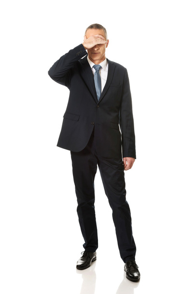 Full length stressed businessman covering his face - Foto, afbeelding